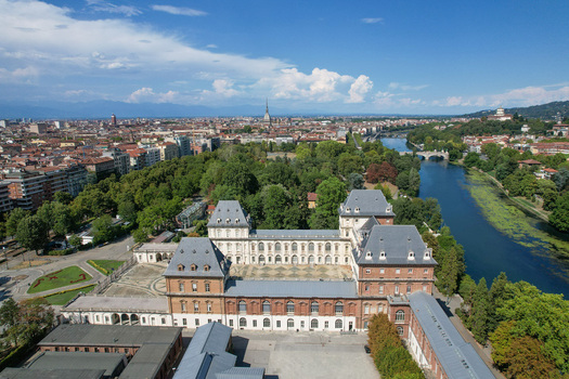 Aerial view of the historic Castello del Valentino building surrounded by lush greenery and the Po River with the city skyline in the background Torino Piemonte Italy. Aerial view of the historic Castello del Valentino building surrounded by lush greenery and the Po River with the city skyline in the background Torino Piemonte Italy.