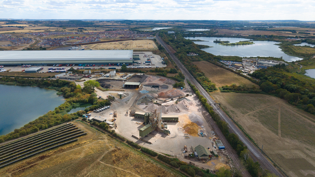 Aerial view of Tarmac Elstow Asphalt facility featuring industrial processing equipment stockpiles of aggregate and surrounding lakes and railway lines in Elstow England United Kingdom. Aerial view of Tarmac Elstow Asphalt facility featuring industrial processing equipment stockpiles of aggregate and surrounding lakes and railway lines in Elstow England United Kingdom.