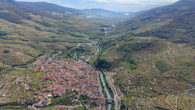 Aerial view of the town nestled in a valley with terracotta roofs contrasting against the lush green valley and distant mountains Cabezuela del Valle Extremadura Spain.