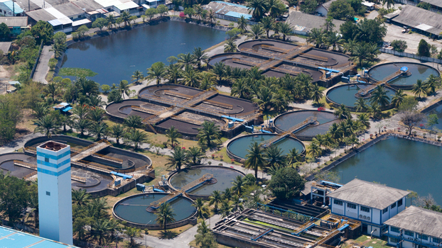 Aerial view of a wastewater treatment plant featuring circular sedimentation tanks and aeration basins surrounded by palm trees in Phuket Phuket Thailand. Aerial view of a wastewater treatment plant featuring circular sedimentation tanks and aeration basins surrounded by palm trees in Phuket Phuket Thailand.