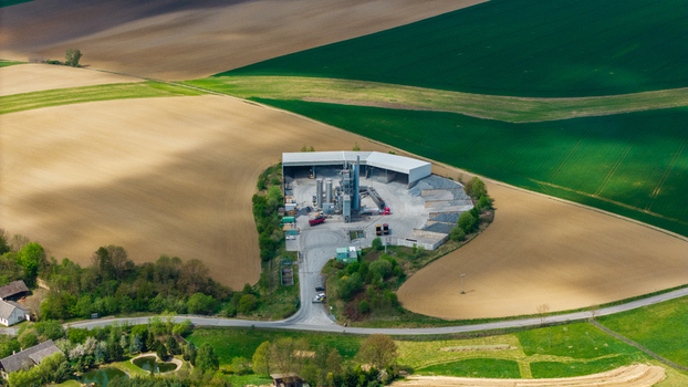 Aerial view of an industrial facility with silos and trucks surrounded by vast agricultural fields and rolling hills in Gruna Pardubicky kraj Czechia. Aerial view of an industrial facility with silos and trucks surrounded by vast agricultural fields and rolling hills in Gruna Pardubicky kraj Czechia.
