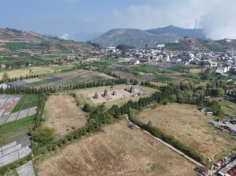 Aerial view of Arjuna Temple complex surrounded by agricultural fields lush green hills and the village of Dieng in Kecamatan Batur Jawa Tengah Indonesia.