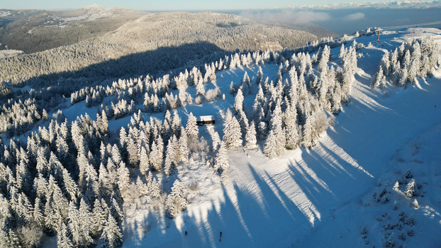 Aerial view of the snow covered pine forest and ski slopes at Col de la Faucille Gex Auvergne Rhone Alpes France. Aerial view of the snow covered pine forest and ski slopes at Col de la Faucille Gex Auvergne Rhone Alpes France.