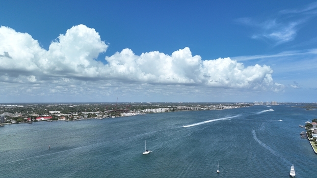 Aerial view of boats sailing through the clear blue waters between the coastlines under a sky filled with fluffy white clouds Clearwater Florida United States.