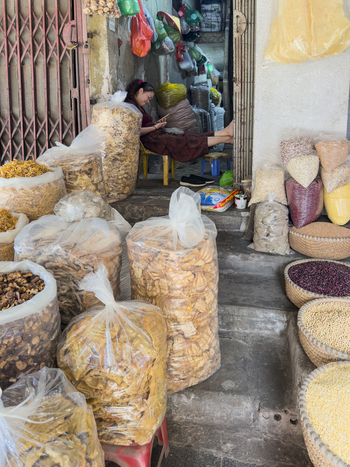 Hanoi Vietnam 11 November 2025 View of a woman sitting in a small shop surrounded by large sacks of dried goods and baskets of grains in the Old Quarter of Hanoi.