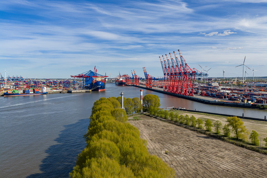Aerial view of Waltershofer Hafen featuring red container cranes cargo ships and stacked containers along the Elbe river in Hamburg Hamburg Germany. Aerial view of Waltershofer Hafen featuring red container cranes cargo ships and stacked containers along the Elbe river in Hamburg Hamburg Germany.