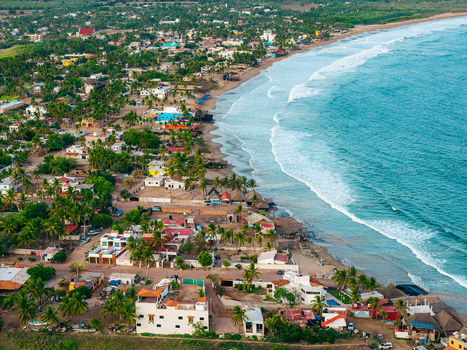 Aerial view of Punta Perula coastal town with sandy beach turquoise ocean waves palm trees and residential buildings in Punta Perula Jalisco Mexico. Aerial view of Punta Perula coastal town with sandy beach turquoise ocean waves palm trees and residential buildings in Punta Perula Jalisco Mexico.