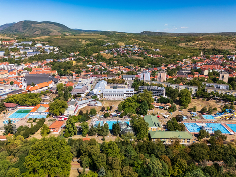 Aerial view of Eger thermal bath complex with outdoor pools water slides and summer visitors surrounded by leafy city neighborhoods and wooded hills in Hungary. Aerial view of Eger thermal bath complex with outdoor pools water slides and summer visitors surrounded by leafy city neighborhoods and wooded hills in Hungary.