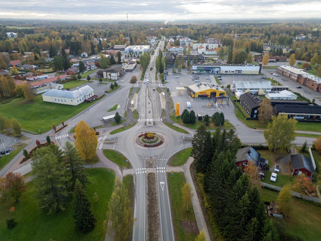 Muhos Finland 22 September 2026 Aerial view of a roundabout in the town center surrounded by low rise buildings green lawns and autumn colored trees under a cloudy sky.