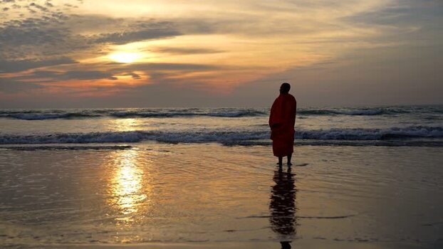 View of a monk standing on the beach at sunset in Bangladesh. View of a monk standing on the beach at sunset in Bangladesh.