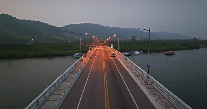 Aerial view of a bridge spanning a river with lush mangrove forests on both sides under a soft evening sky Thailand. Aerial view of a bridge spanning a river with lush mangrove forests on both sides under a soft evening sky Thailand.