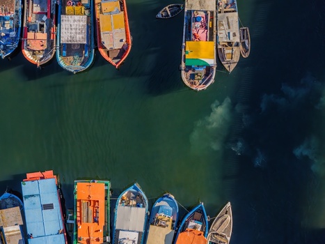 Aerial view of colorful fishing boats moored at Quadrado da Urca in the harbor with calm green water and shadows cast on the surface in Rio de Janeiro Rio de Janeiro Brazil.