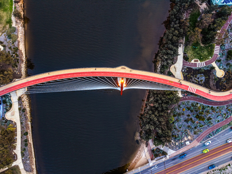 Aerial view of Boorloo Bridge spanning the Swan River with its red path and cable stayed design surrounded by parklands and urban infrastructure in East Perth Western Australia Australia.