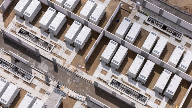 Aerial view of the Zarnowiec Pumped Storage Power Plant featuring rows of white containerized battery energy storage systems on concrete pads in Wejherowo County Pomeranian Voivodeship Poland.