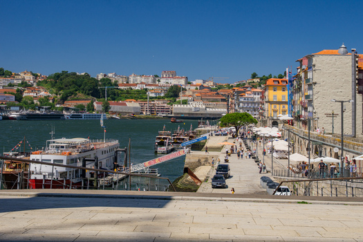 Porto Portugal 13 July 2021 View of the vibrant Ribeira district where colorful buildings meet the Douro River under a clear blue sky with boats docked along the pier. Porto Portugal 13 July 2021 View of the vibrant Ribeira district where colorful buildings meet the Douro River under a clear blue sky with boats docked along the pier.