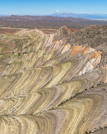 Aerial view of the Gigantes Dormidos geological formation showcasing intricate colorful rock strata and folded sedimentary layers under a clear blue sky in Tres Cruces Jujuy Province Argentina. Aerial view of the Gigantes Dormidos geological formation showcasing intricate colorful rock strata and folded sedimentary layers under a clear blue sky in Tres Cruces Jujuy Province Argentina.