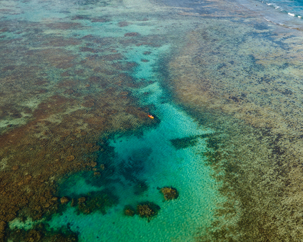 Aerial view of a vibrant turquoise channel cutting through a reef where a solitary kayak rests amidst the contrasting textures Goro South Province New Caledonia. Aerial view of a vibrant turquoise channel cutting through a reef where a solitary kayak rests amidst the contrasting textures Goro South Province New Caledonia.