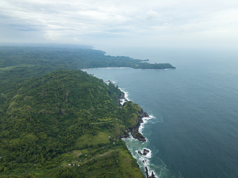 Aerial view of the rugged coastline where emerald forests meet the turquoise sea Pengilon Hill Gunungkidul Regency Daerah Istimewa Yogyakarta Indonesia. Aerial view of the rugged coastline where emerald forests meet the turquoise sea Pengilon Hill Gunungkidul Regency Daerah Istimewa Yogyakarta Indonesia.