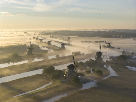 Aerial view of the historic windmills of Unesco World Heritage Kinderdijk surrounded by morning mist and canals during a golden sunrise Kinderdijk Zuid Holland Netherlands.