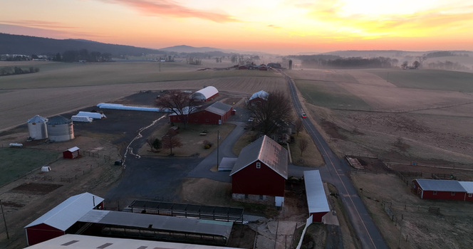 Aerial view of Penryn farmland featuring red barns silos and rolling fields under a vibrant sunrise sky in Penryn Pennsylvania United States. Aerial view of Penryn farmland featuring red barns silos and rolling fields under a vibrant sunrise sky in Penryn Pennsylvania United States.