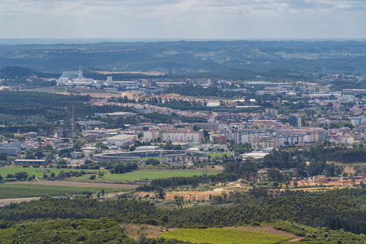 View of the town of Rio Maior featuring residential buildings industrial zones and surrounding green landscapes under a clear sky in Rio Maior Santarem Portugal. View of the town of Rio Maior featuring residential buildings industrial zones and surrounding green landscapes under a clear sky in Rio Maior Santarem Portugal.