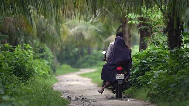 View of a couple on a motorcycle on a rural path Bangladesh. View of a couple on a motorcycle on a rural path Bangladesh.