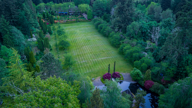 Aerial view of a large manicured lawn and garden area near Northwest Skyline Boulevard surrounded by lush forest and dense evergreen trees in Portland Oregon United States. Aerial view of a large manicured lawn and garden area near Northwest Skyline Boulevard surrounded by lush forest and dense evergreen trees in Portland Oregon United States.