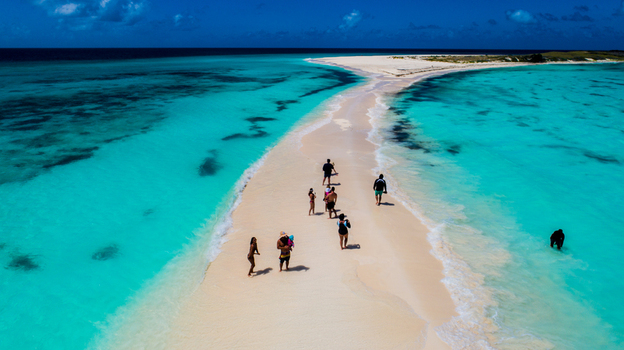 Aerial view of Los Roques archipelago featuring a white sandbar surrounded by turquoise waters with people walking along the shore in Los Roques Dependencias Federales Venezuela. Aerial view of Los Roques archipelago featuring a white sandbar surrounded by turquoise waters with people walking along the shore in Los Roques Dependencias Federales Venezuela.