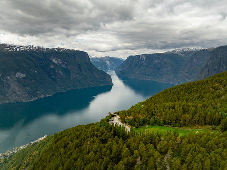 Aerial view of Stegastein Lookout overlooking the Aurlandsfjord with steep mountains lush green forests and calm deep blue water in Aurland Vestland Norway.