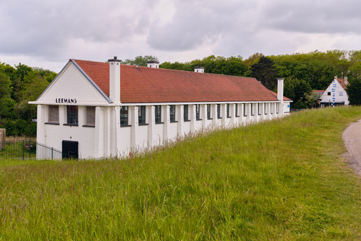 Wieringerwerf Netherlands 17 May 2026 View of Gemaal Leemans pumping station with its white facade and red tiled roof behind a grassy embankment under a cloudy sky.
