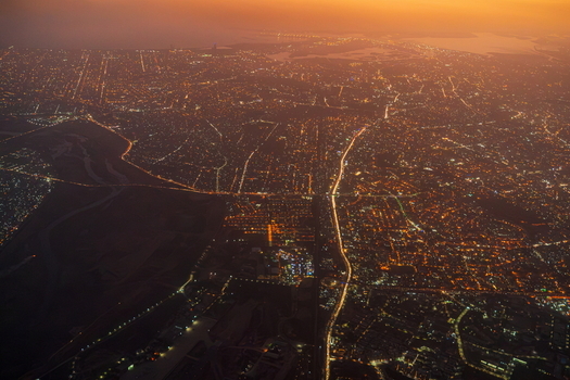 Aerial view of the sprawling urban landscape of Karachi at night with glowing street lights illuminating the dense road network and city infrastructure in Karachi Sindh Pakistan.