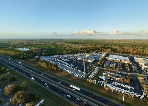 Aerial view of an RV dealership lot with rows of white RVs contrasting against the surrounding green forest and a multi lane highway St. Augustine Florida United States. Aerial view of an RV dealership lot with rows of white RVs contrasting against the surrounding green forest and a multi lane highway St. Augustine Florida United States.