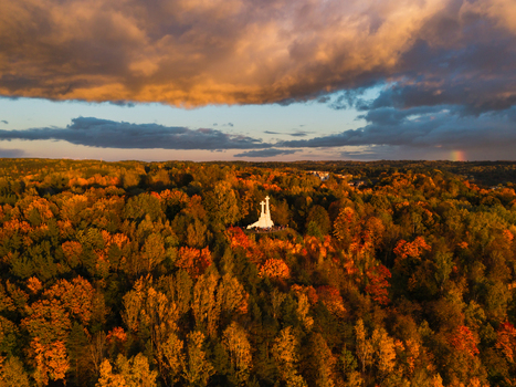 Aerial view of the Three Crosses monument standing prominently amidst a sea of autumnal foliage bathed in the soft glow of the setting sun Vilnius Lithuania. Aerial view of the Three Crosses monument standing prominently amidst a sea of autumnal foliage bathed in the soft glow of the setting sun Vilnius Lithuania.