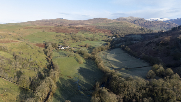 Aerial view of lush green fields and rolling hills a patchwork of shadows and sunlight paint a serene landscape Ambleside England United Kingdom. Aerial view of lush green fields and rolling hills a patchwork of shadows and sunlight paint a serene landscape Ambleside England United Kingdom.