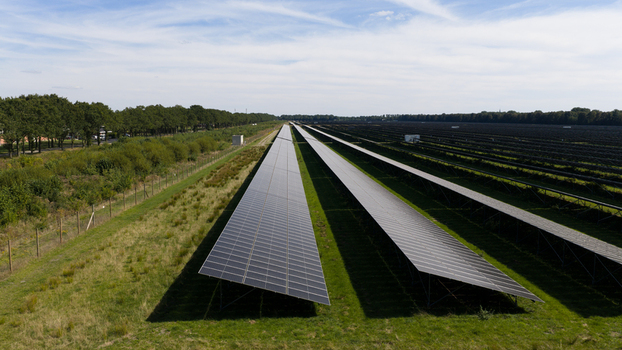 Aerial view of Zonnepark Pekela featuring long rows of solar panels installed in a green field in Oude Pekela Groningen Netherlands. Aerial view of Zonnepark Pekela featuring long rows of solar panels installed in a green field in Oude Pekela Groningen Netherlands.