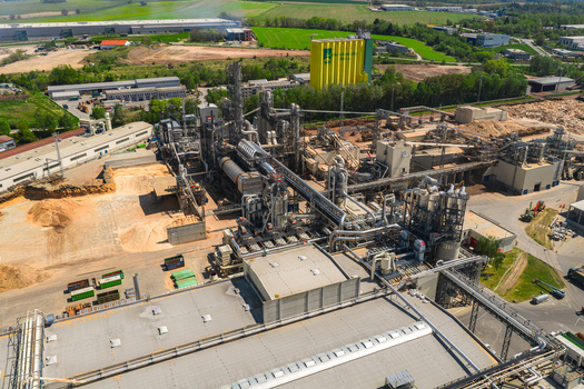 Aerial view of an industrial wood processing plant with complex piping systems and sawdust storage areas Jihlava Vysocina Region Czechia.