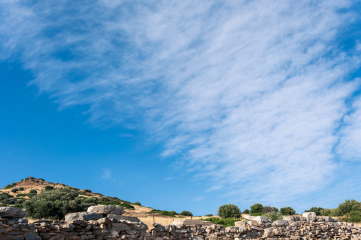 View of the ancient stone walls and ruins of the archaeological site under a blue sky with wispy clouds in Thoricus Greece.