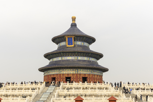 View of the Hall of Prayer for Good Harvests in the Temple of Heaven with tourists walking on white marble terraces under a hazy sky Beijing Beijing China. View of the Hall of Prayer for Good Harvests in the Temple of Heaven with tourists walking on white marble terraces under a hazy sky Beijing Beijing China.
