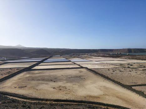 Aerial view of the geometric salt evaporation ponds of Salinas de Janubio surrounded by arid volcanic landscape under a clear blue sky in Lanzarote Canarias Spain. Aerial view of the geometric salt evaporation ponds of Salinas de Janubio surrounded by arid volcanic landscape under a clear blue sky in Lanzarote Canarias Spain.