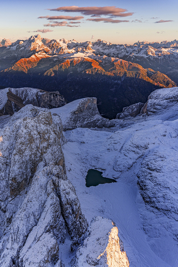 Aerial view of snow dusted peaks kissed by the sun s fiery glow serene Antermoia lake nestled amidst rugged icy terrain creating a breathtaking alpine panorama Canazei Trentino South Tyrol Italy.
