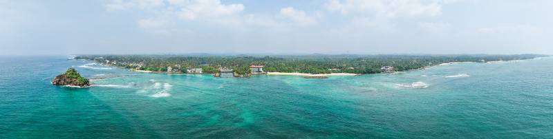 Aerial view of Devil s Rock formation turquoise ocean waves and lush tropical coastline with palm trees Sri Lanka.