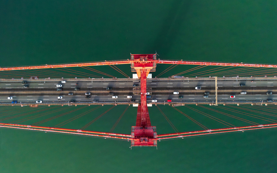 Aerial view of the 25 de Abril Bridge with traffic flowing across the red suspension structure over the Tagus River in Lisbon Lisbon Portugal.