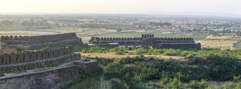 View of Rohtas Fort with its historic stone battlements and defensive walls overlooking the surrounding landscape and distant town in Dina Punjab Pakistan. View of Rohtas Fort with its historic stone battlements and defensive walls overlooking the surrounding landscape and distant town in Dina Punjab Pakistan.