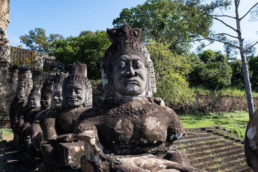 View of ancient stone statues of asuras and devas lining the causeway at the entrance of Angkor Thom with weathered carvings in Krong Siem Reap Siem Reap Province Cambodia. View of ancient stone statues of asuras and devas lining the causeway at the entrance of Angkor Thom with weathered carvings in Krong Siem Reap Siem Reap Province Cambodia.