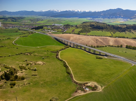 Aerial view of the D1 motorway viaduct crossing green fields and rolling hills with snow capped mountains in the distance Likavka Zilina Region Slovakia. Aerial view of the D1 motorway viaduct crossing green fields and rolling hills with snow capped mountains in the distance Likavka Zilina Region Slovakia.