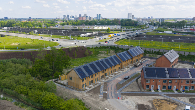 Aerial view of modern residential houses with solar panels on roofs near a highway and city skyline in Utrecht Utrecht Netherlands.
