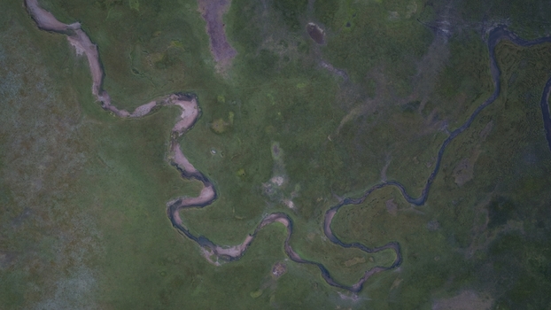 Aerial view of the winding river at Song Kul surrounded by lush green meadows in Naryn Region Kyrgyzstan. Aerial view of the winding river at Song Kul surrounded by lush green meadows in Naryn Region Kyrgyzstan.