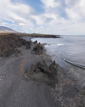 Aerial view of Djupalonssandur beach with its distinctive black volcanic sand and jagged rock formations along the rugged coastline in Iceland. Aerial view of Djupalonssandur beach with its distinctive black volcanic sand and jagged rock formations along the rugged coastline in Iceland.