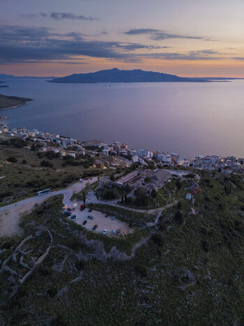 Aerial view of Lekuresi Castle overlooking the coastal town of Saranda at sunset with the Ionian Sea and distant hills in the background Saranda Vlore County Albania. Aerial view of Lekuresi Castle overlooking the coastal town of Saranda at sunset with the Ionian Sea and distant hills in the background Saranda Vlore County Albania.