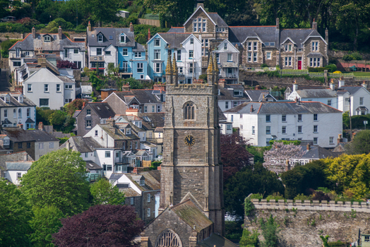 View of the historic town of Fowey featuring the prominent church tower colorful residential buildings and surrounding greenery in Fowey Cornwall United Kingdom. View of the historic town of Fowey featuring the prominent church tower colorful residential buildings and surrounding greenery in Fowey Cornwall United Kingdom.